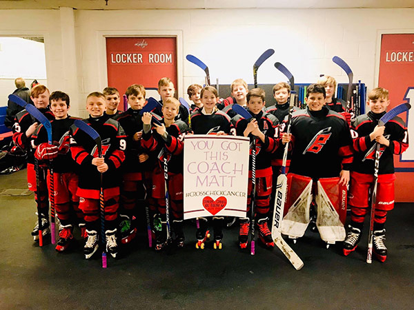 Kids hockey team with sign for coach