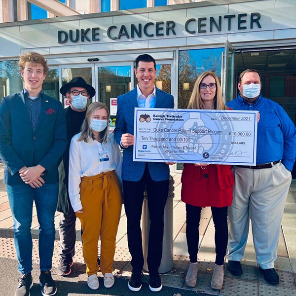 Photo of a group of people with Matt Cross holding giant check at the Duke Cancer Center Donation Ceremony